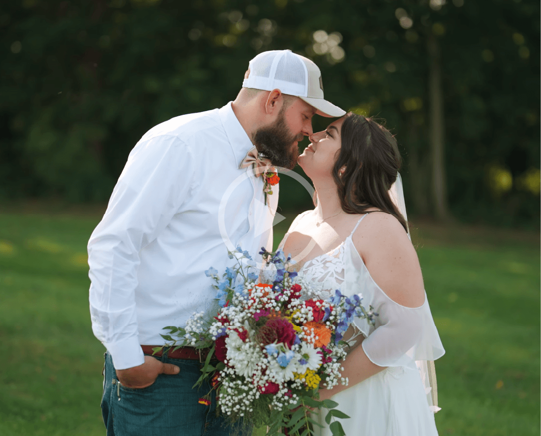 Bride and groom kissing in a grassy garden, bride holding a colorful bouquet