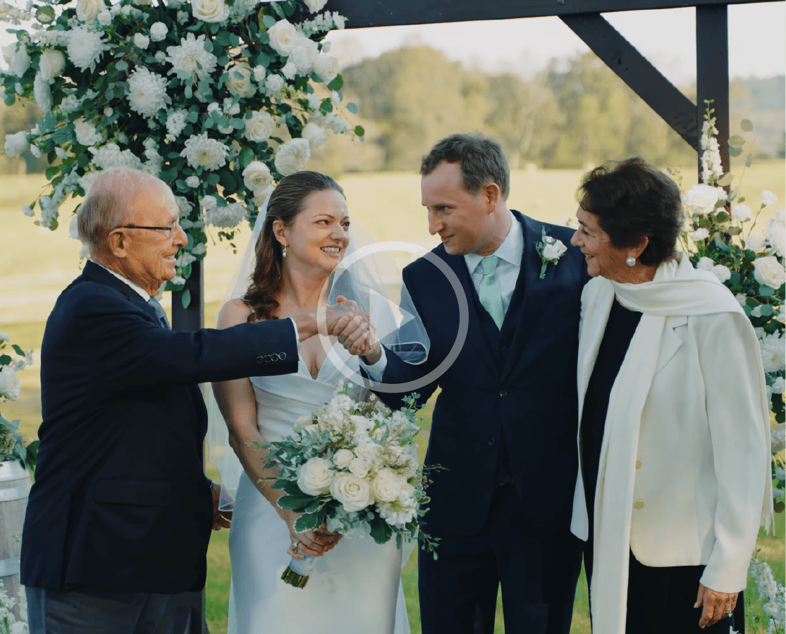 Outdoor wedding ceremony under a white floral arch