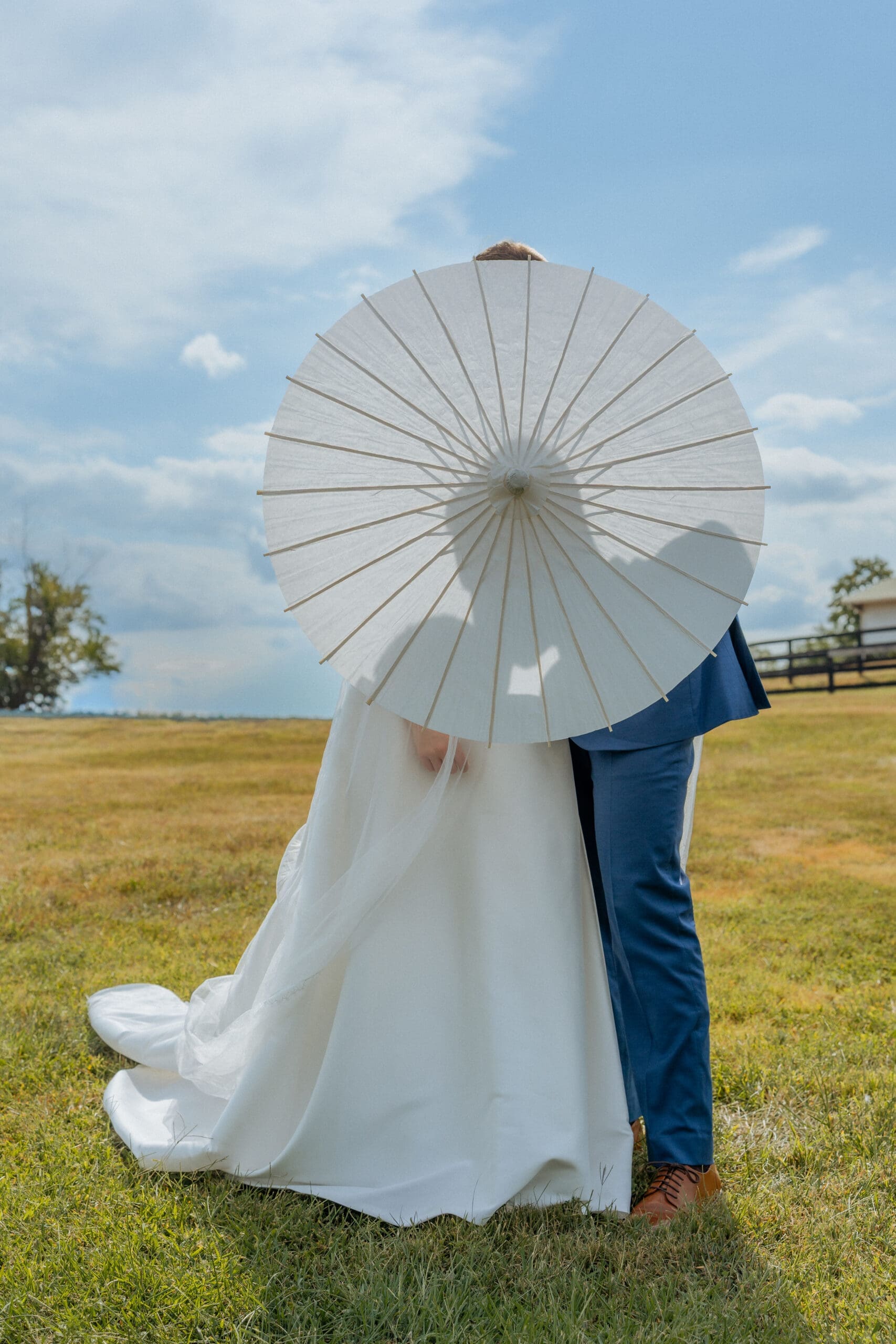 Bride and groom under a white parasol with mountain views