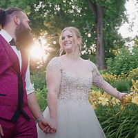 A bride and groom pose together outdoors during golden hour in a garden setting, captured in an intimate wedding portrait.