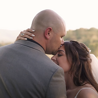 A couple shares an intimate embrace during golden hour with soft, warm lighting and a blurred natural background.