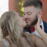 A couple shares an intimate moment indoors during the holiday season, with warm Christmas lights visible in the background.