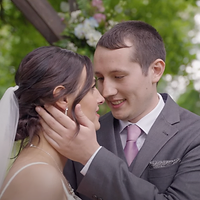 A bride and groom share an intimate moment during their wedding ceremony in an outdoor garden setting with blooming white flowers in the background.