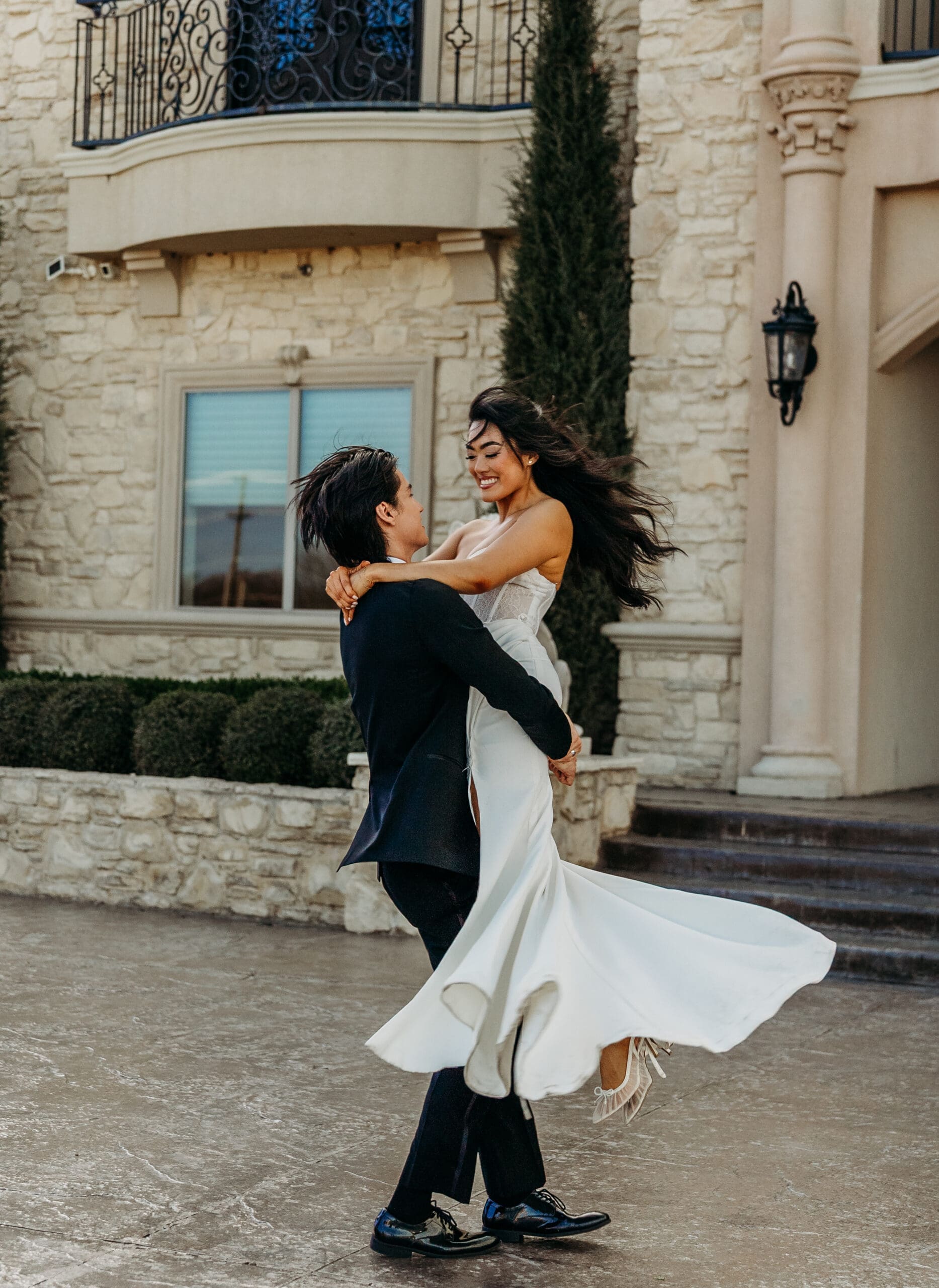 Couple in formal wedding attire dancing in front of an elegant building