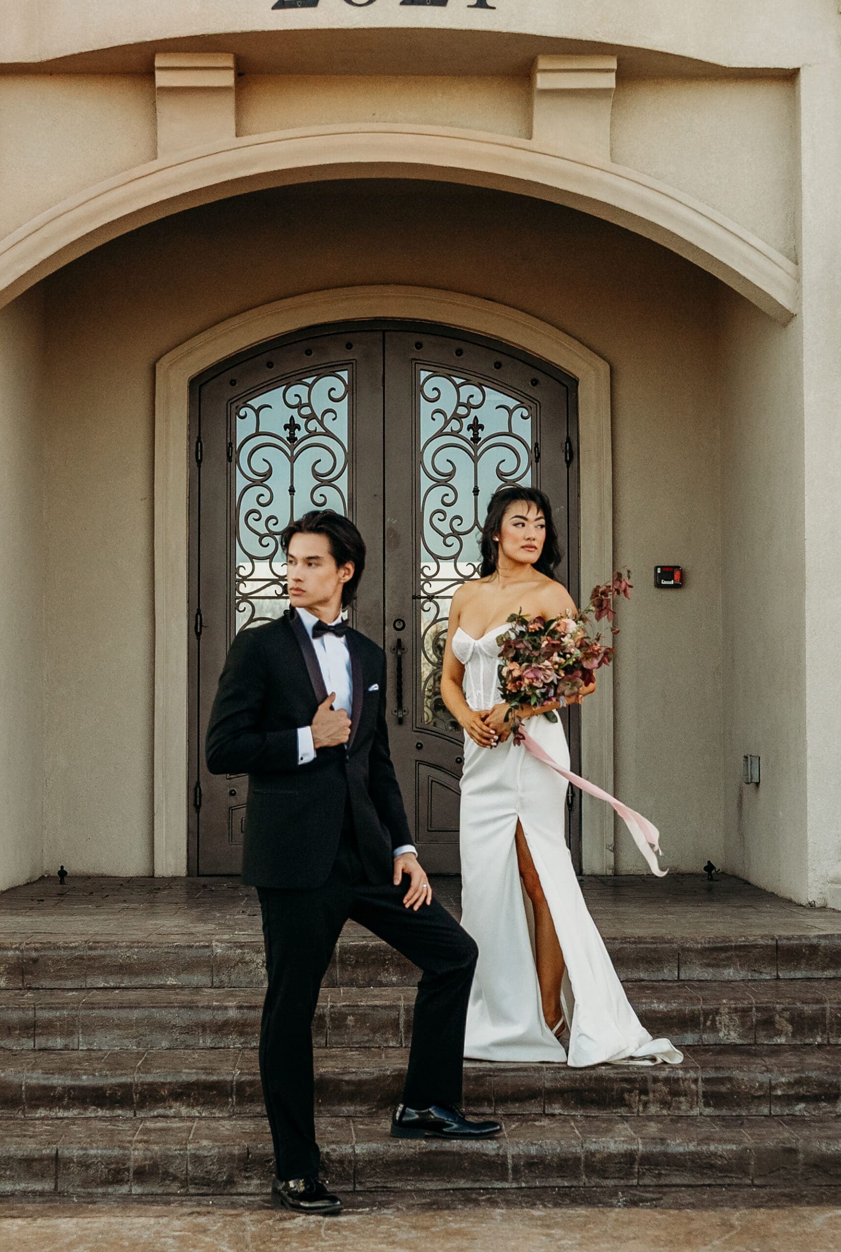 Bride and groom on stone steps in front of a historic building