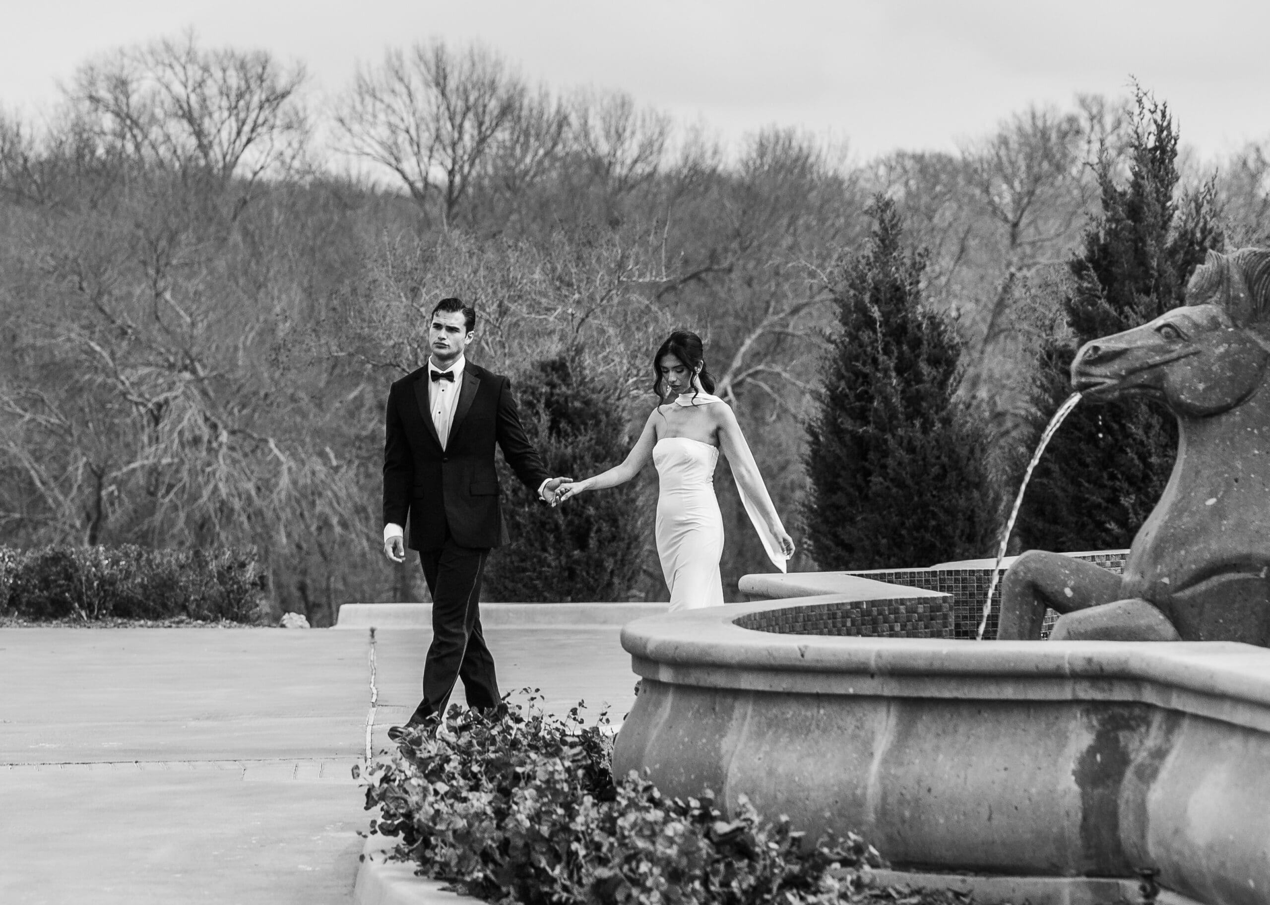 Bride and groom holding hands beside an ornate fountain