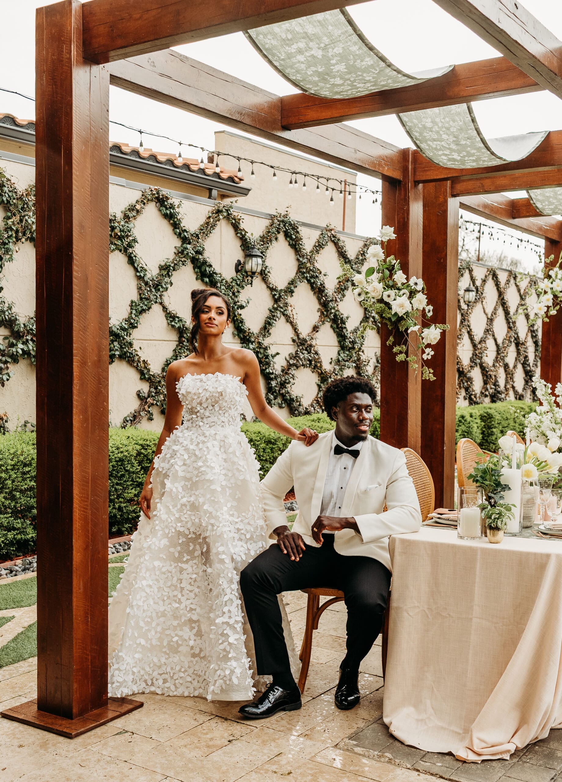 Bride and groom sitting together under a wooden pergola