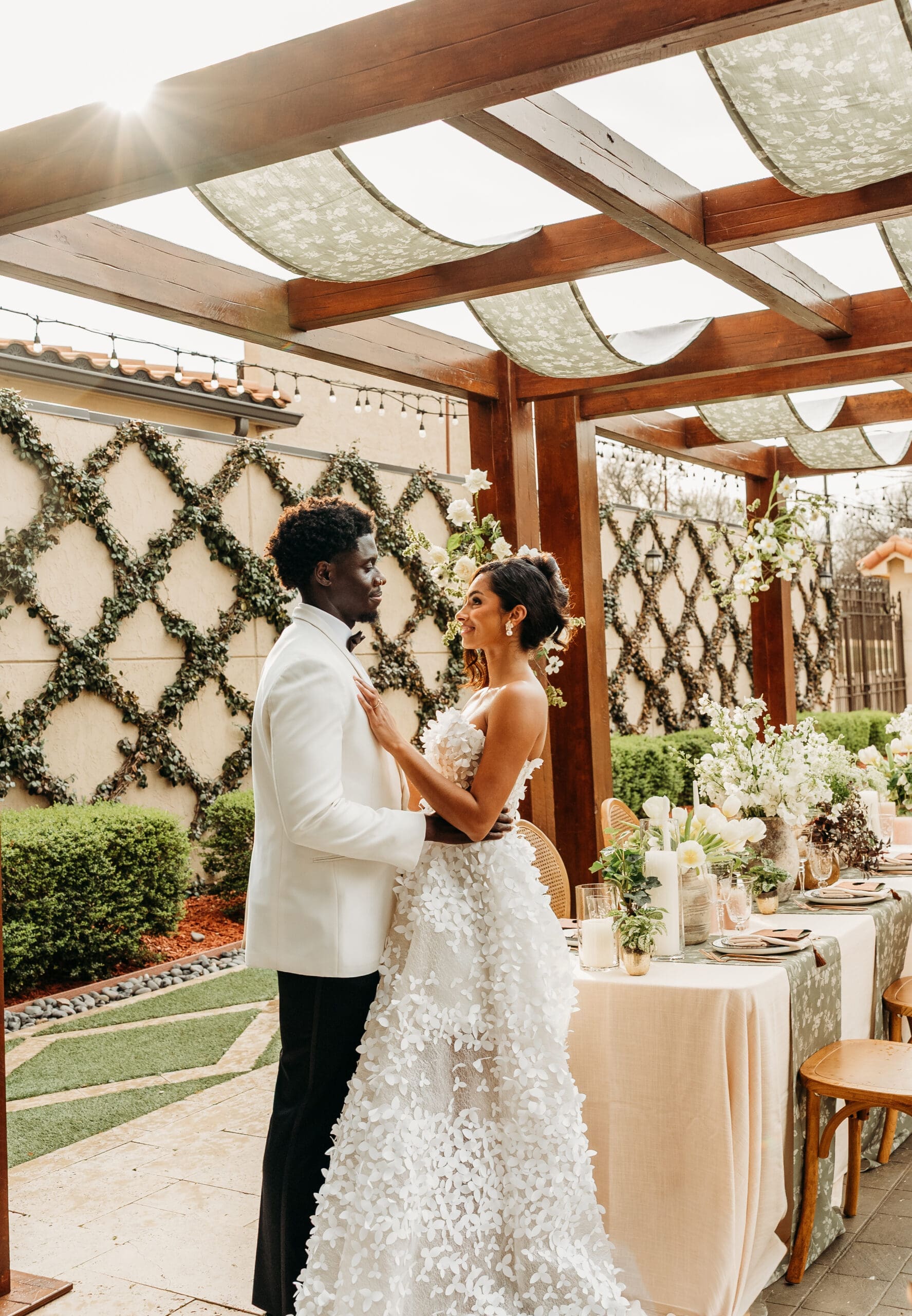 Bride and groom embrace under a wooden pergola at an elegant venue